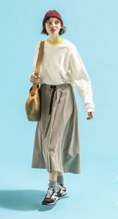 Woman in a beanie, long sleeve shirt, and midi skirt with a shoulder bag