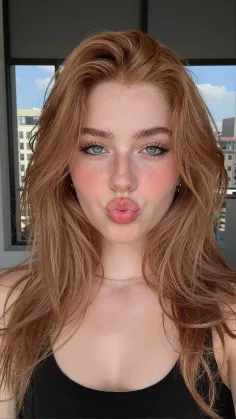Woman with red hair and blue eyes making a kissy face indoors