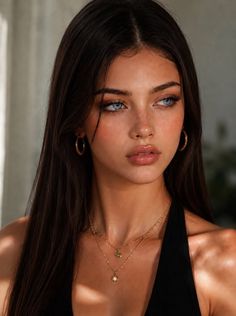 Woman with long dark hair and blue eyes wearing gold jewelry