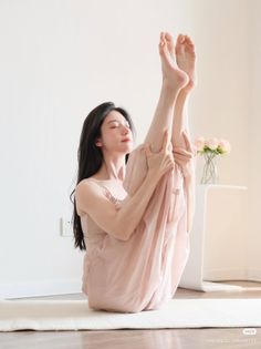Woman in a pink dress doing a yoga pose indoors with soft lighting