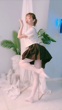 Woman in a school uniform and white tights posing indoors with a cat tail