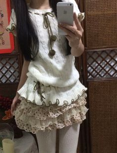 Person in a white sweater and polka dot ruffle skirt taking a mirror selfie