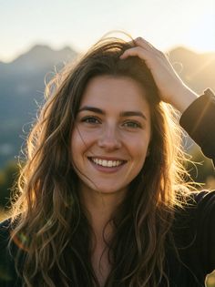 Smiling woman with long hair backlit by the setting sun outdoors