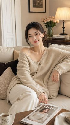 Woman in a beige cardigan sitting on a sofa with soft lighting