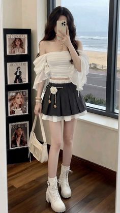 Woman in an off-shoulder top and pleated skirt taking a mirror selfie indoors