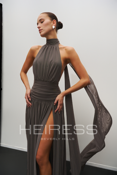 Woman in a gray halter dress with a high slit in a studio setting