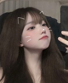 Woman with long hair and bangs taking a selfie with a cat ears filter