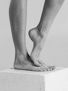 Black and white photograph of bare feet and legs on a white block