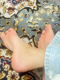 Bare feet on a patterned rug with light wash jeans