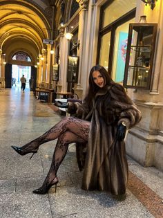 Woman in a fur coat and lace stockings posing indoors