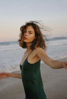 Woman with windblown hair in a green dress on a beach