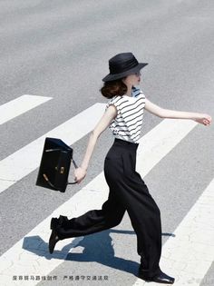 Woman in a black hat and striped shirt crossing a street