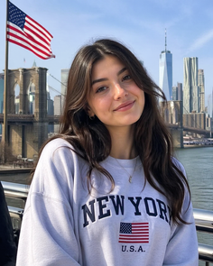 Woman in a New York sweatshirt with the Brooklyn Bridge and cityscape in the background