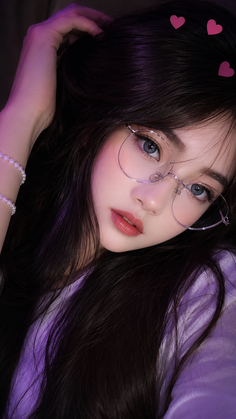 Woman with long dark hair and glasses, wearing a pearl bracelet