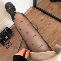 Person wearing black tights with butterfly pattern and mary jane shoes