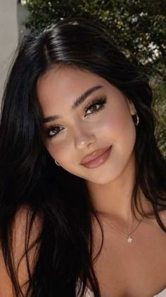 Woman with long dark hair and hoop earrings smiling at the camera