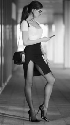 Woman in a white top and black slit skirt with high heels and glasses