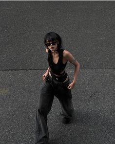 Woman with black hair and sunglasses wearing a crop top and baggy jeans outdoors