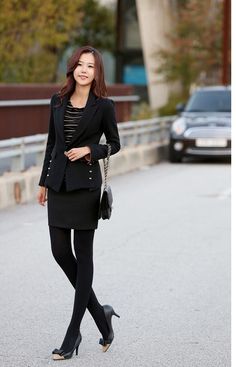 Woman in a black suit and skirt with tights and high heels outdoors