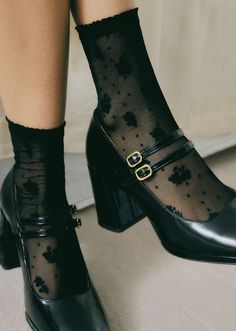 Close up of feet wearing black mary janes and sheer floral socks