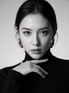 Woman in a black turtleneck and earrings posing in a studio