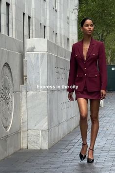 Woman in a maroon skirt suit walking on a city street