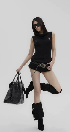 Woman in a black distressed top and shorts with boots and sunglasses