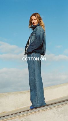 Woman in a denim jacket and wide-leg jeans against a blue sky