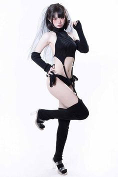 Woman in black lingerie with a veil and thigh-high socks posing on a white background