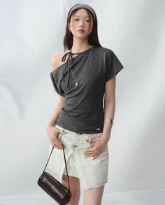 Woman with long hair wearing an off-shoulder top and white skirt in a studio