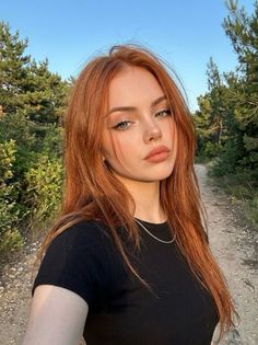 Woman with long red hair wearing a black shirt outdoors