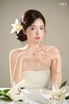 Woman in a white dress with a lily in her hair, posing indoors