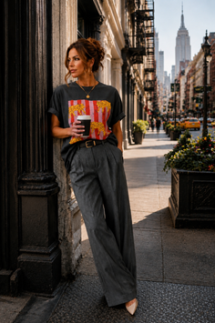 Woman in a t-shirt and wide leg pants holding a coffee cup on a city street