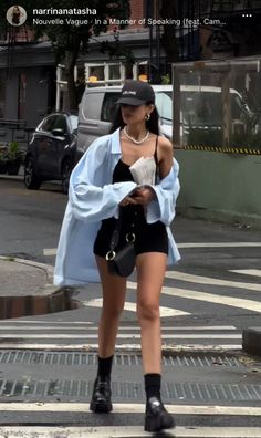 Woman in black shorts and a light blue shirt walking on a street
