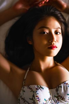 Woman with long dark hair and red lipstick wearing a floral top, looking at camera