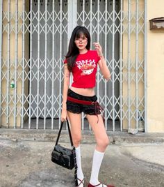 Woman in a red crop top and lace shorts posing outdoors