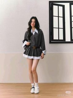 Woman with long dark hair wearing a collared shirt and mini skirt indoors