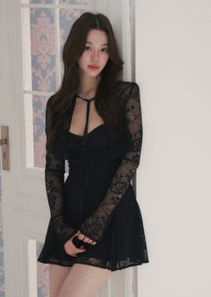 Woman in a black lace dress with long hair leaning against a wall