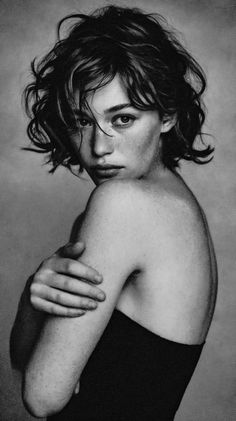 Woman with short curly hair and freckles, looking over her shoulder