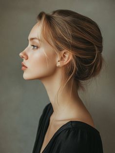 Woman with blonde hair in an updo wearing a black top, in profile view