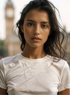 Woman with long hair in a white t-shirt outdoors with a blurred background