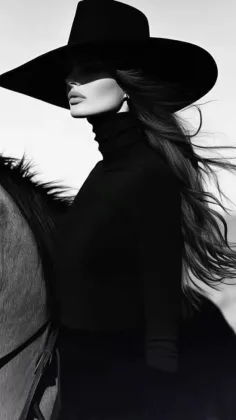 Woman in a wide brim hat and turtleneck on horseback in black and white
