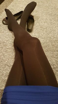 Person wearing black tights and a blue skirt with ballet flats on a carpeted floor