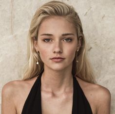 Woman with blonde hair and pearl earrings wearing a black top