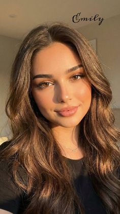 Woman with long brown hair and dimples in soft golden hour lighting