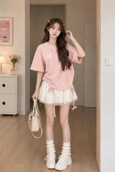 Woman in a pink t-shirt and white mini skirt with leg warmers indoors