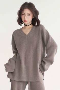 Woman with short brown hair wearing a V-neck sweater and choker indoors