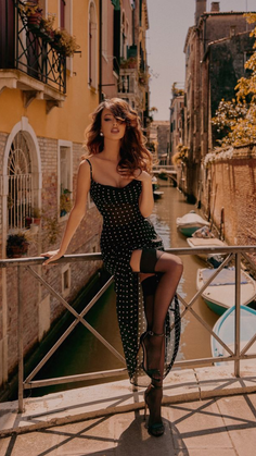 Woman in a polka dot dress and stockings posing on a bridge over a Venice canal