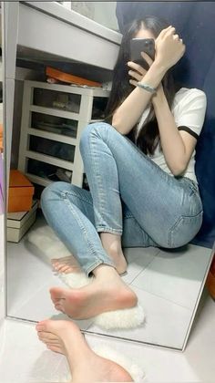 Person with long hair taking a mirror selfie while sitting on the floor
