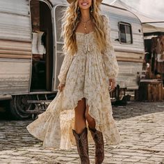 Woman in a floral dress and cowboy boots smiling outdoors